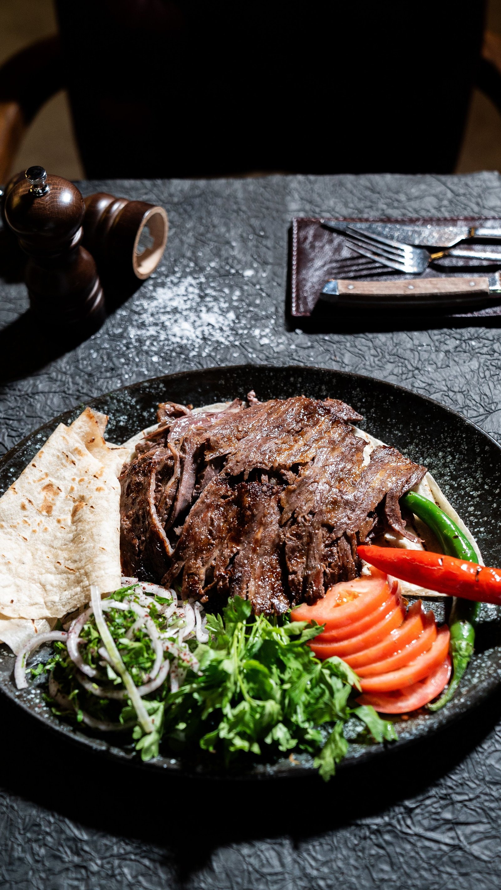 Ahşap masada siyah tabakta servis edilmiş yemek